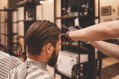 hairdresser is applying hair spray to the client’s hair. barber using hair spray
