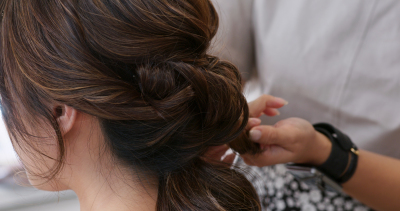 Hairdresser creating a hairstyle for bride in salon