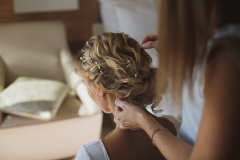 The stylist does the bride's hair at the hotel.